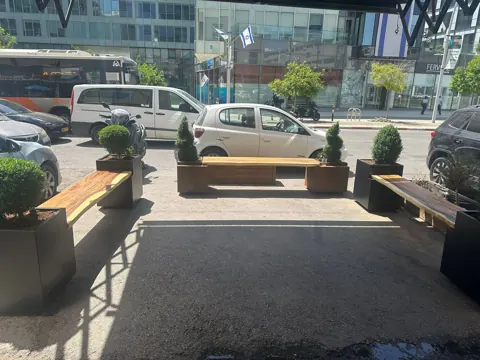 אדניות ספסל מפלדה שחורה ועץ לאורך רחוב