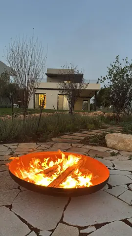 קערת אש מקורטן בוערת בחצר מרוצפת אבן